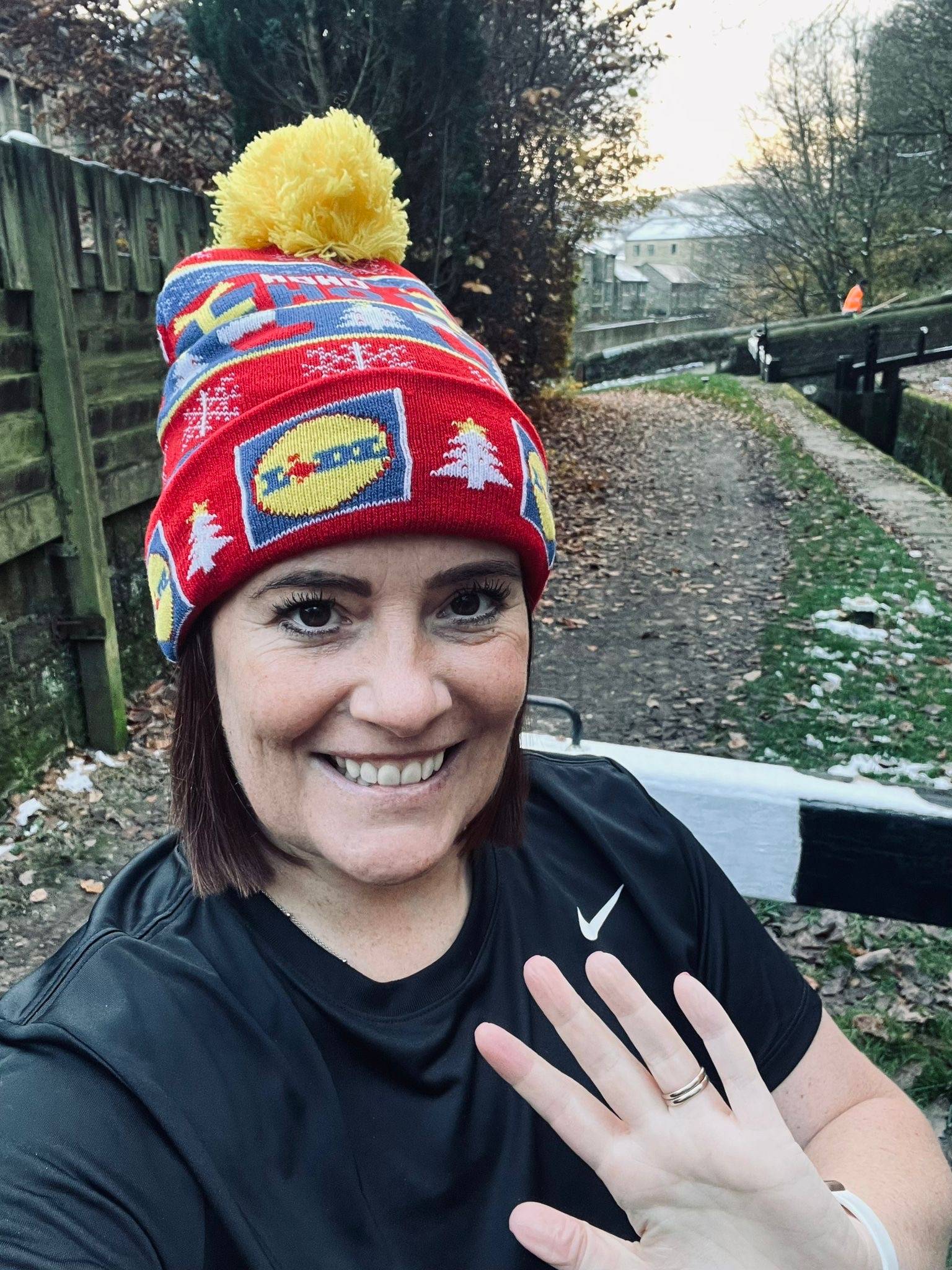 Woman in Lidl hat and Nike top by a canal.