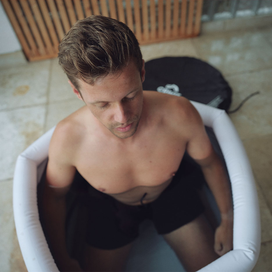 Man in an inflatable ice bath tub, looking down.