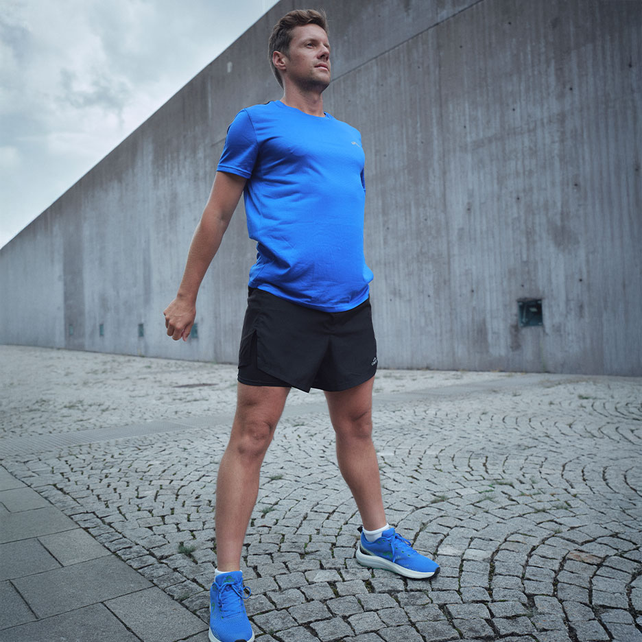 Man in blue t-shirt and black shorts, ready for a run.