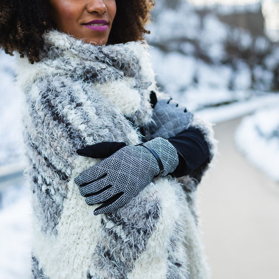 Woman in a faux fur coat and patterned gloves in a snowy landscape.