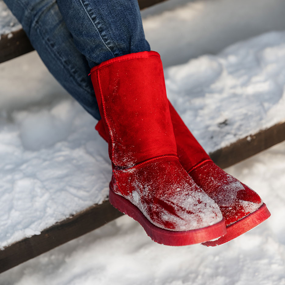 Red winter boots in snow and jeans