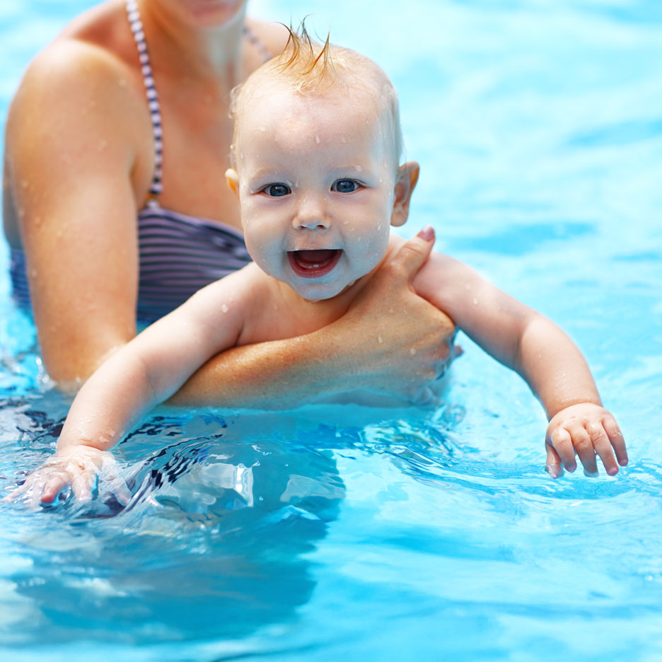 Baby swimming in a pool with its mother.