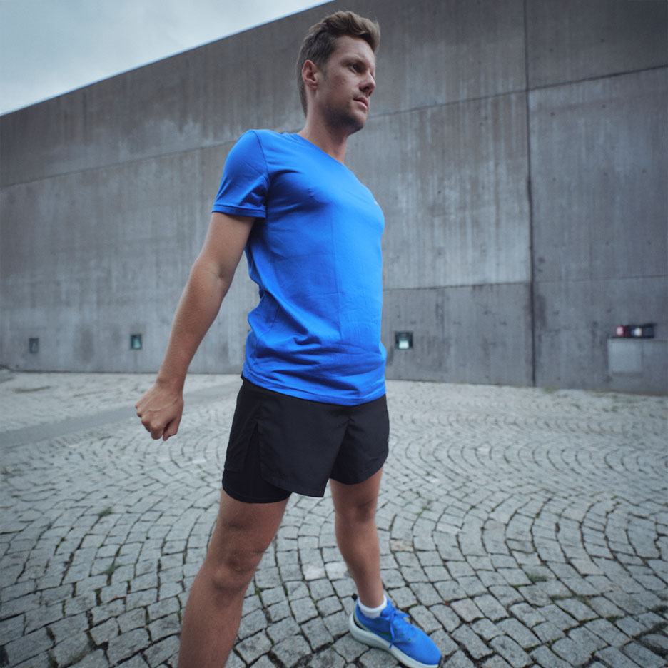 Man in blue t-shirt and black shorts, preparing for exercise.