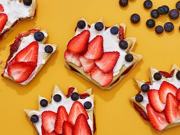 Crown-shaped cookies with strawberries, blueberries, and cream.