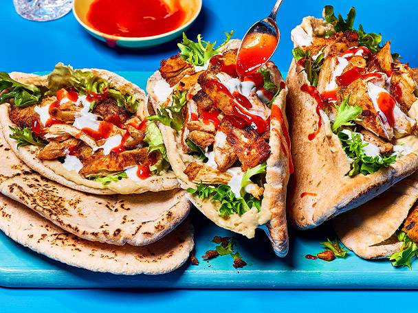 Chicken pita bread with hummus and sauce.