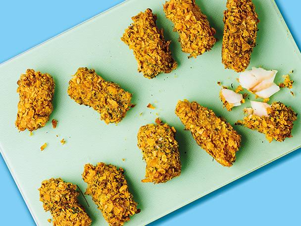 Crispy fish fingers on a green board.