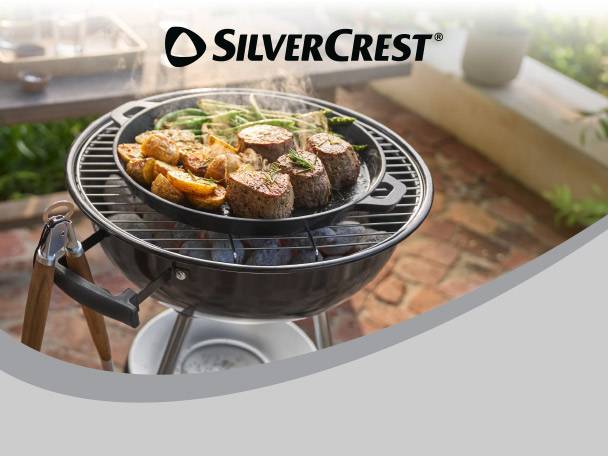 Barbecue with a pan of grilled meat, potatoes, and vegetables, with a logo in the top right.