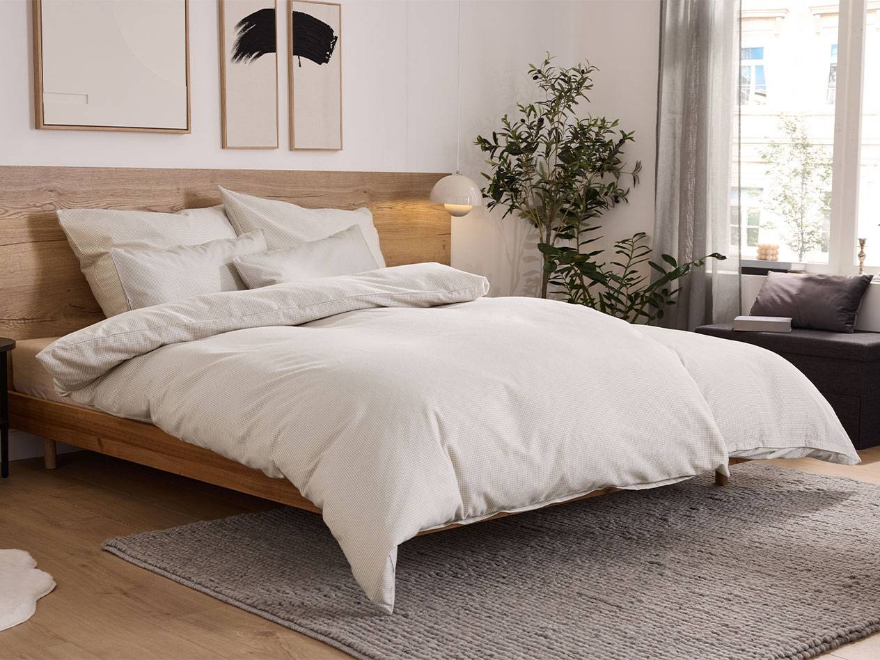 Bedroom with a wooden bed, white bedding, and a grey rug.