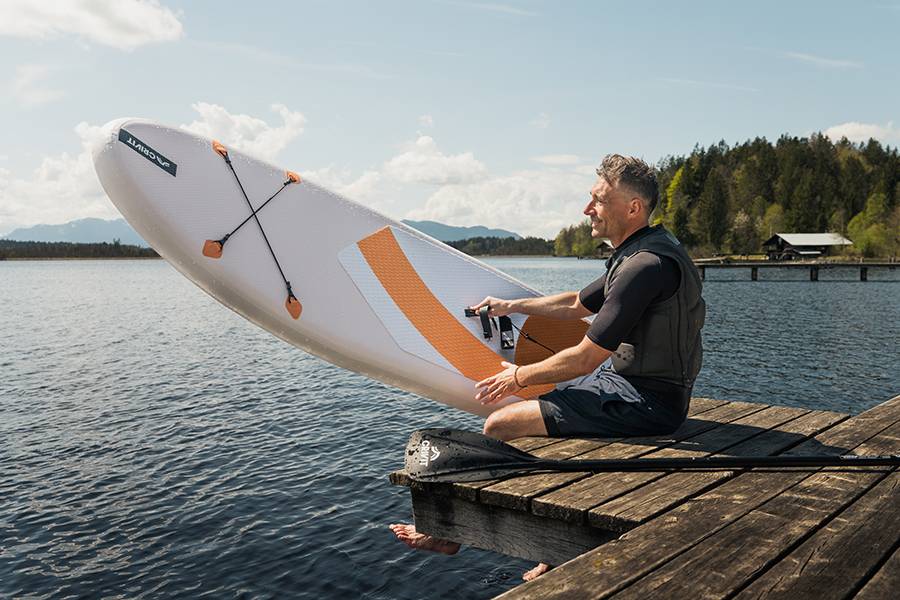 Aquamarina paddleboard and paddle by a lake.