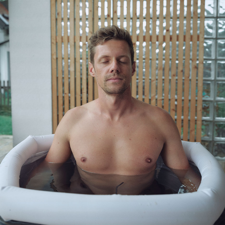 Man with closed eyes in an outdoor inflatable bathtub.