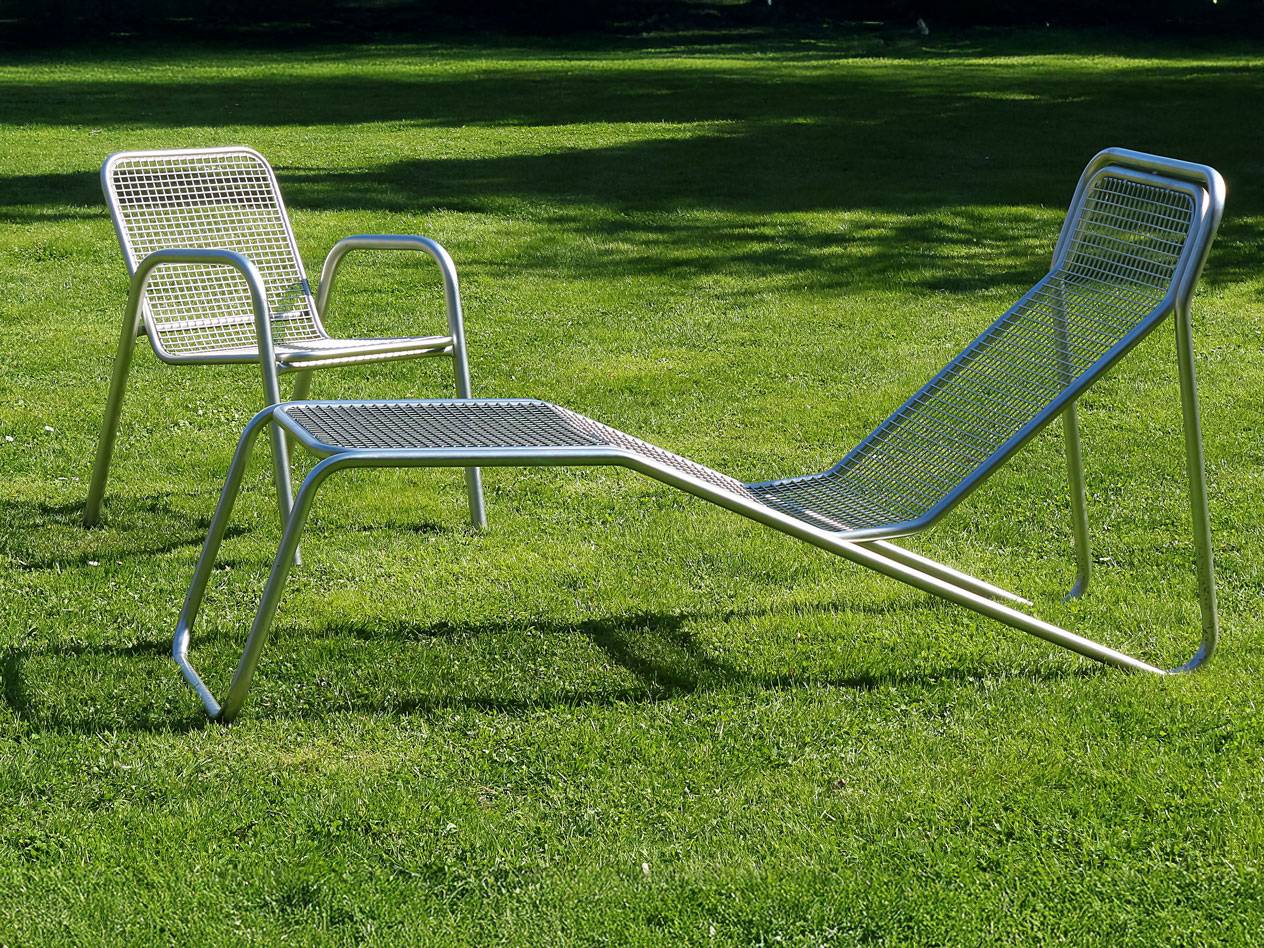 Metal chaise lounge and chair on grass.