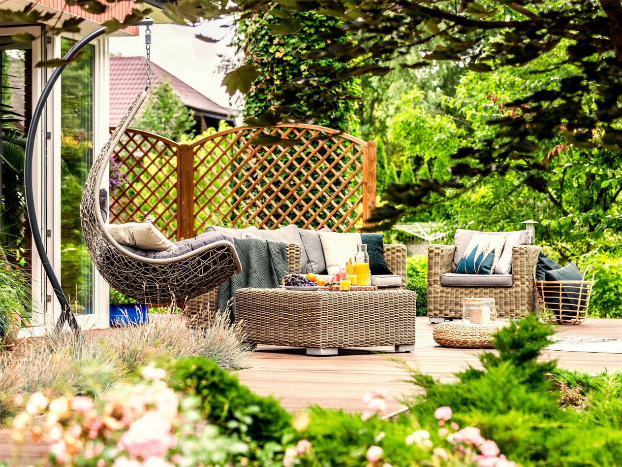 Hanging chair, wicker sofa and coffee table in a garden setting.
