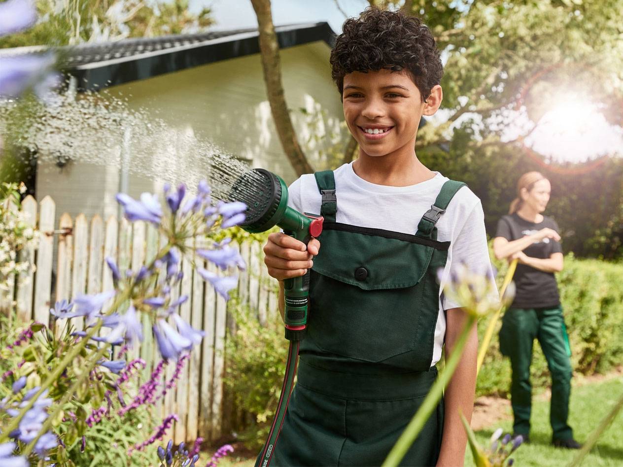 Boy watering flowers with a Gardena hose.