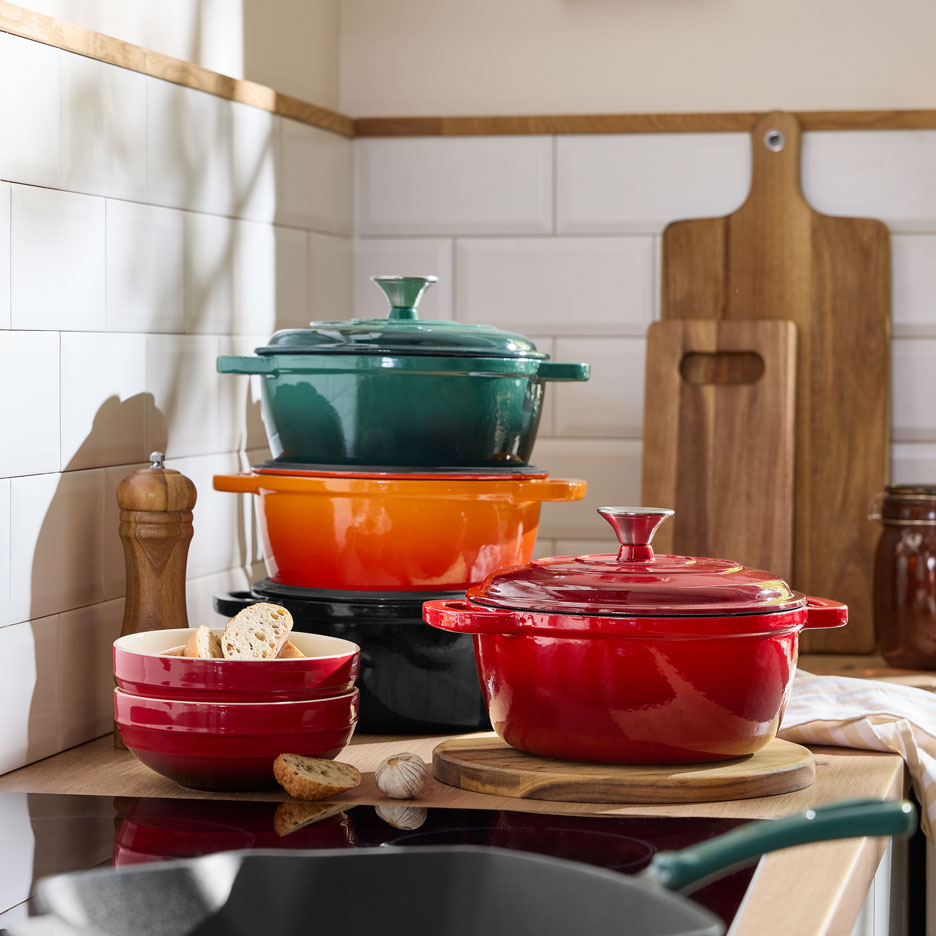 Colorful cast iron Dutch ovens and bowls on a kitchen counter.