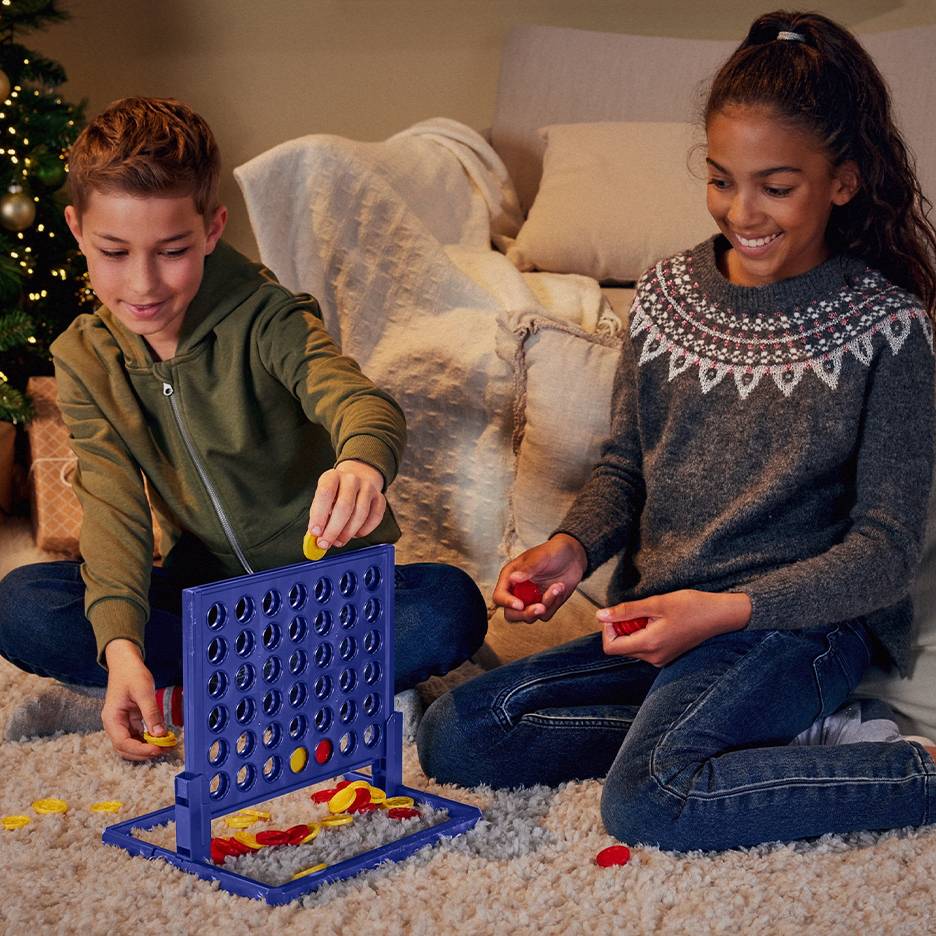 Two children play Connect Four in a living room.