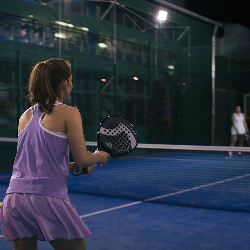 Padel: Woman with paddle racket on court.