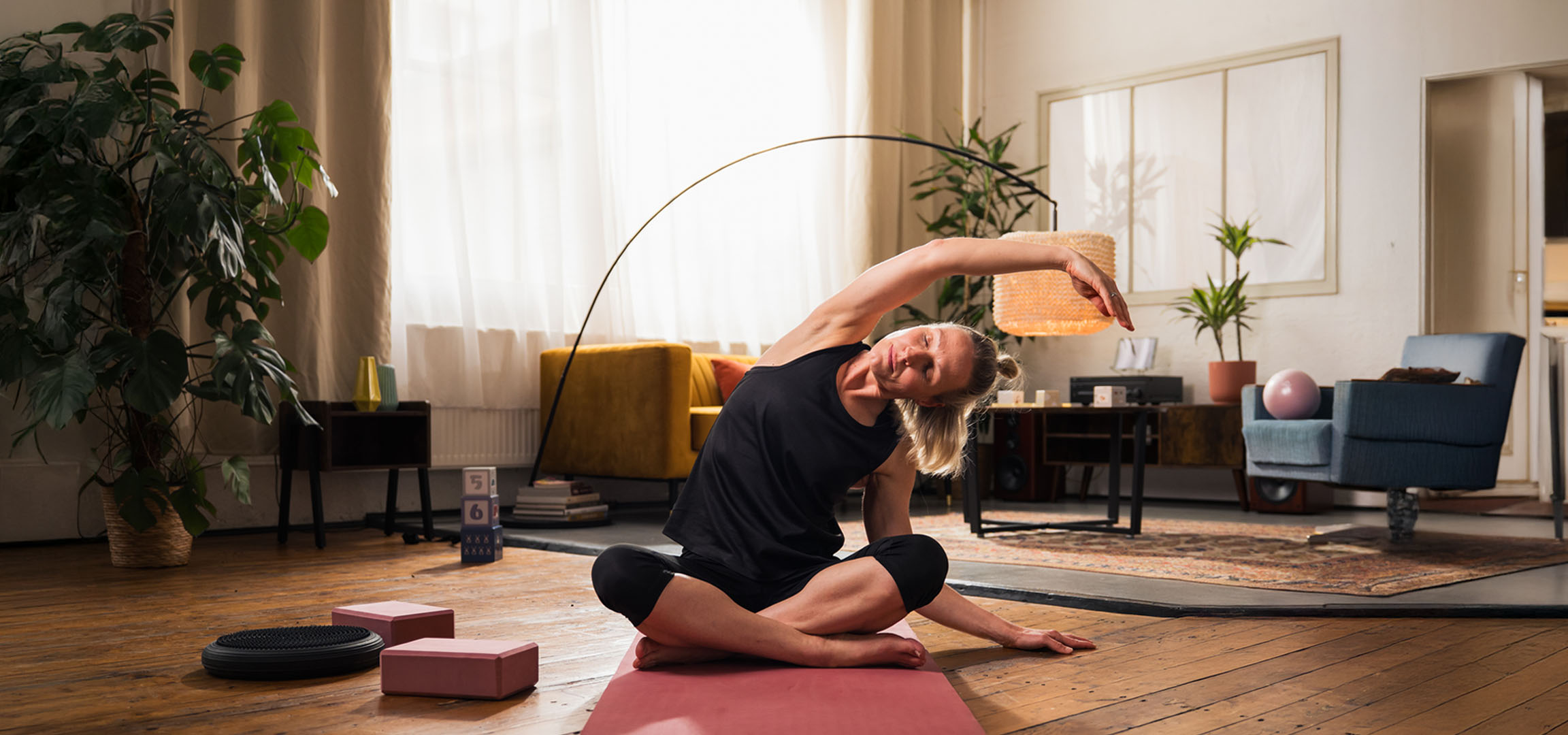 Woman doing yoga at home with mat and blocks.