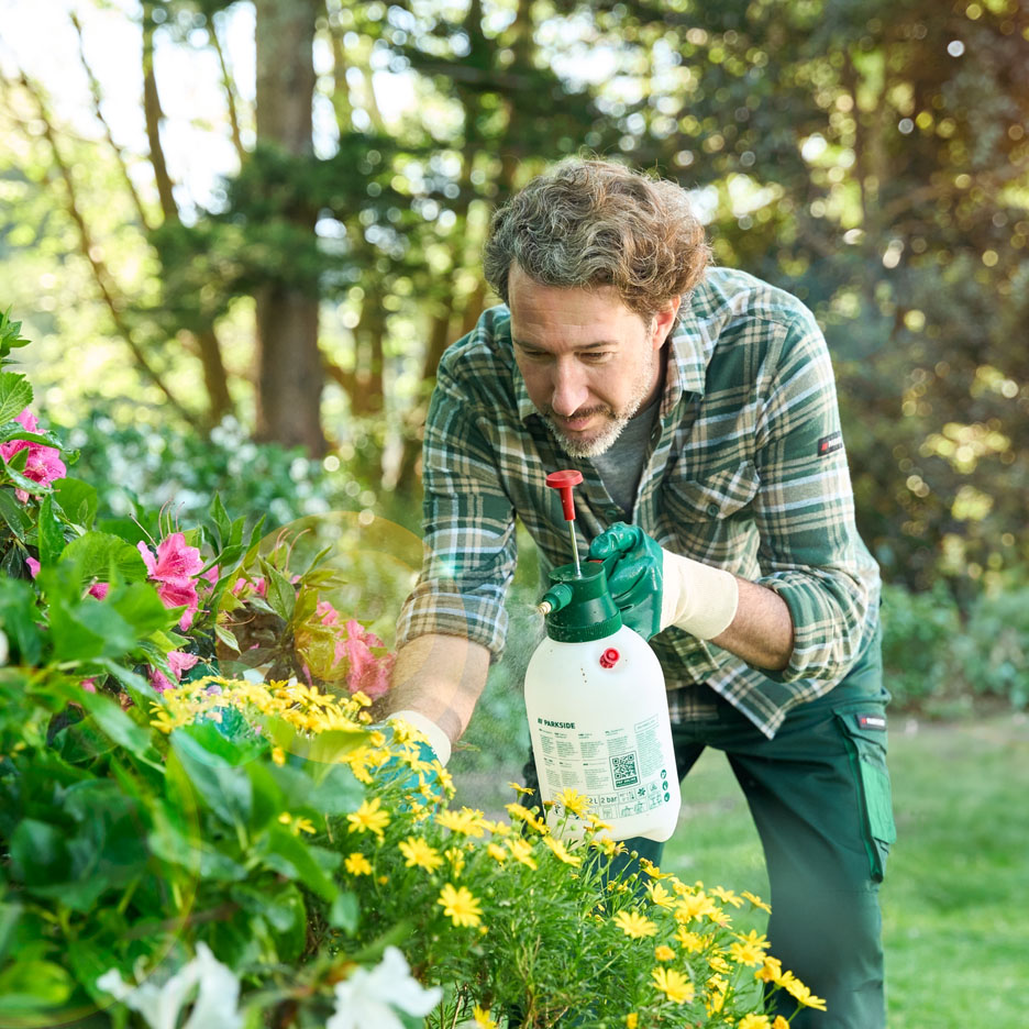 Man spraying flowers with a Parkside sprayer.