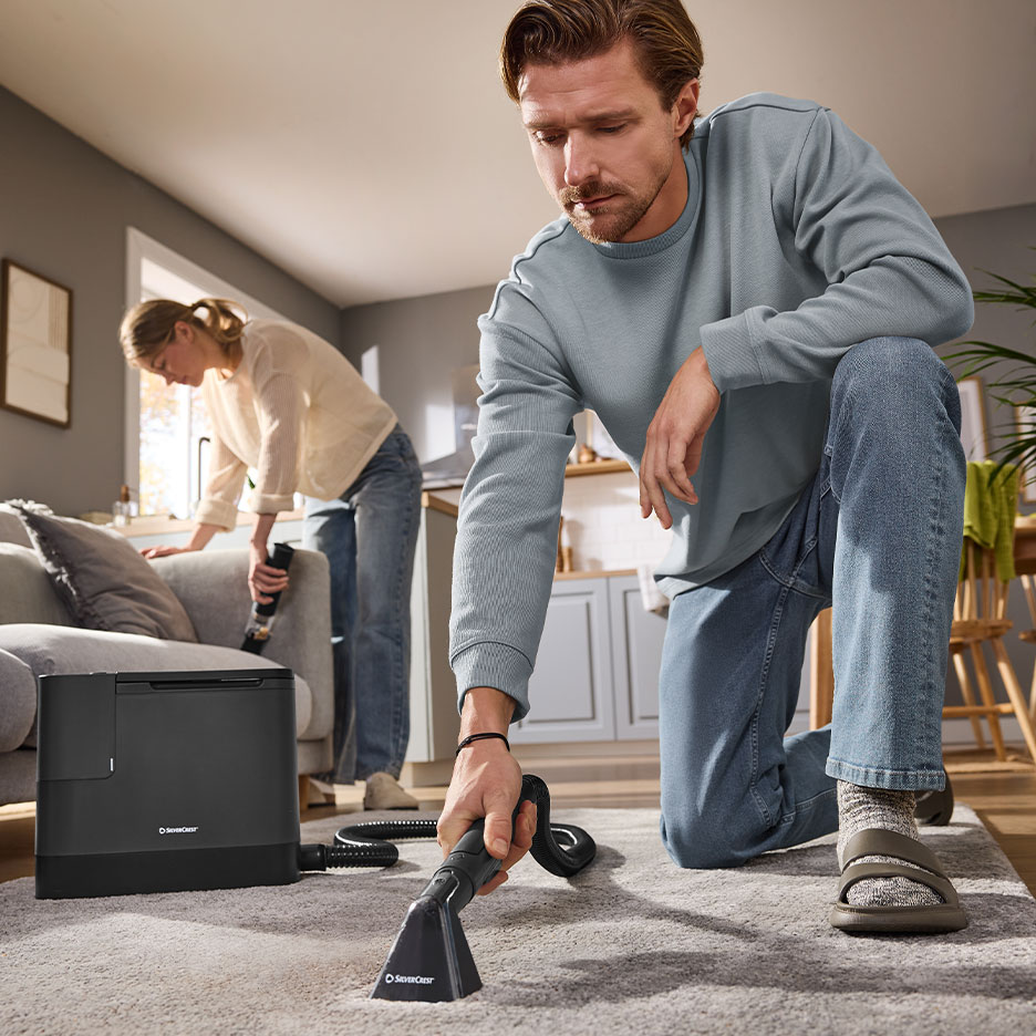 Man and woman cleaning home with SilverCrest carpet and upholstery cleaner.