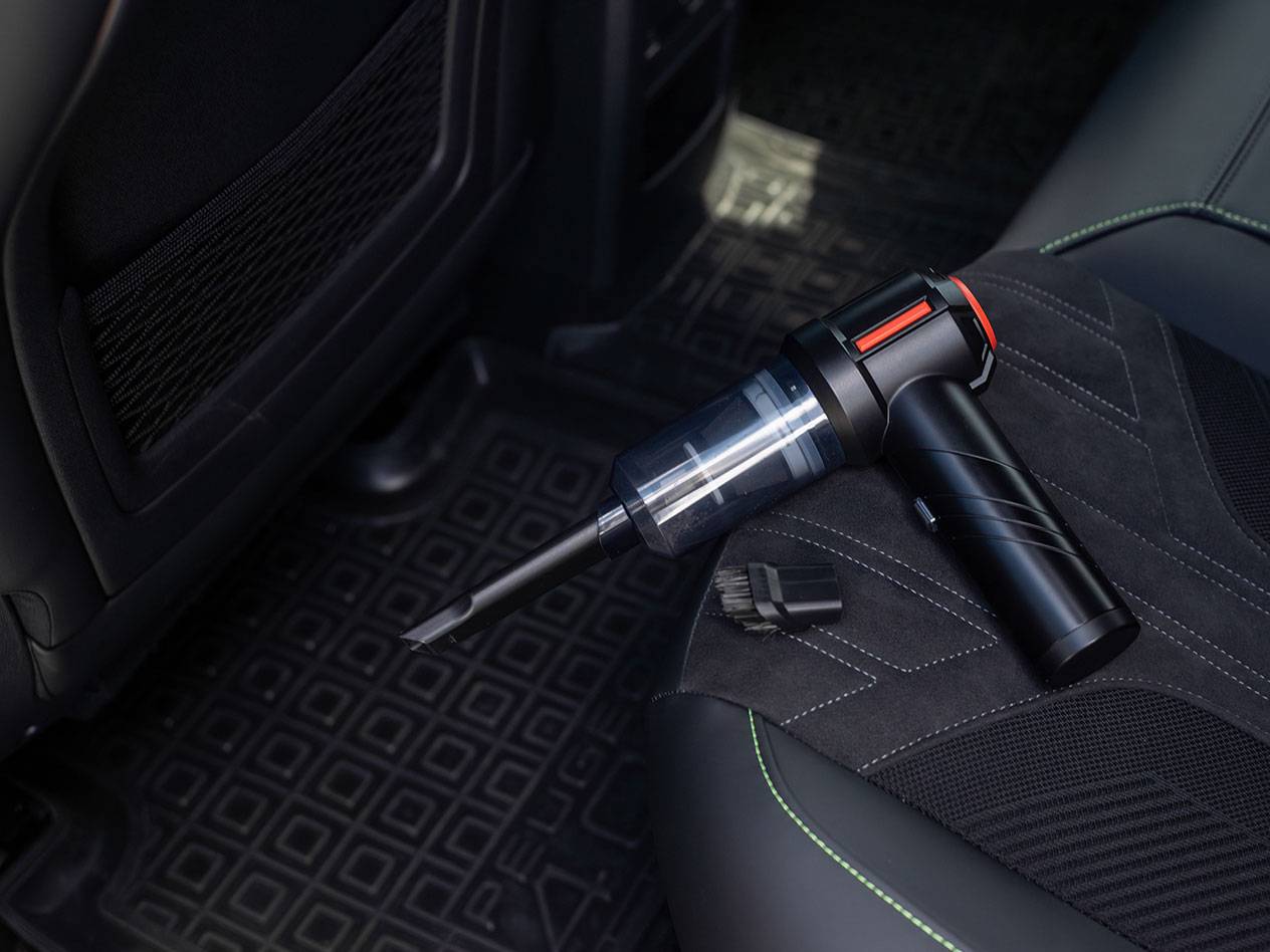 Compact handheld vacuum cleaner with accessories on a car seat.