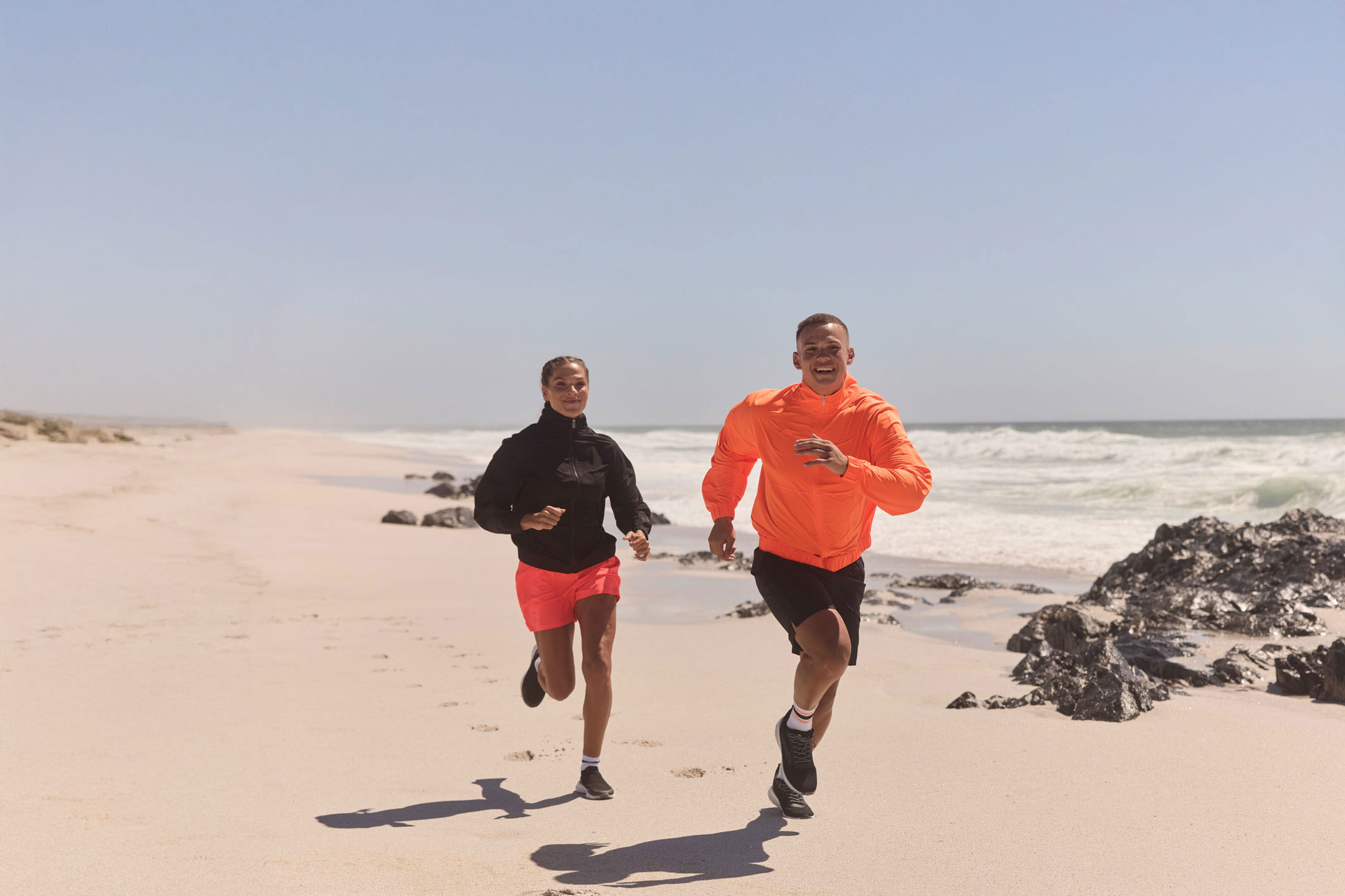 Two people jogging on the beach.