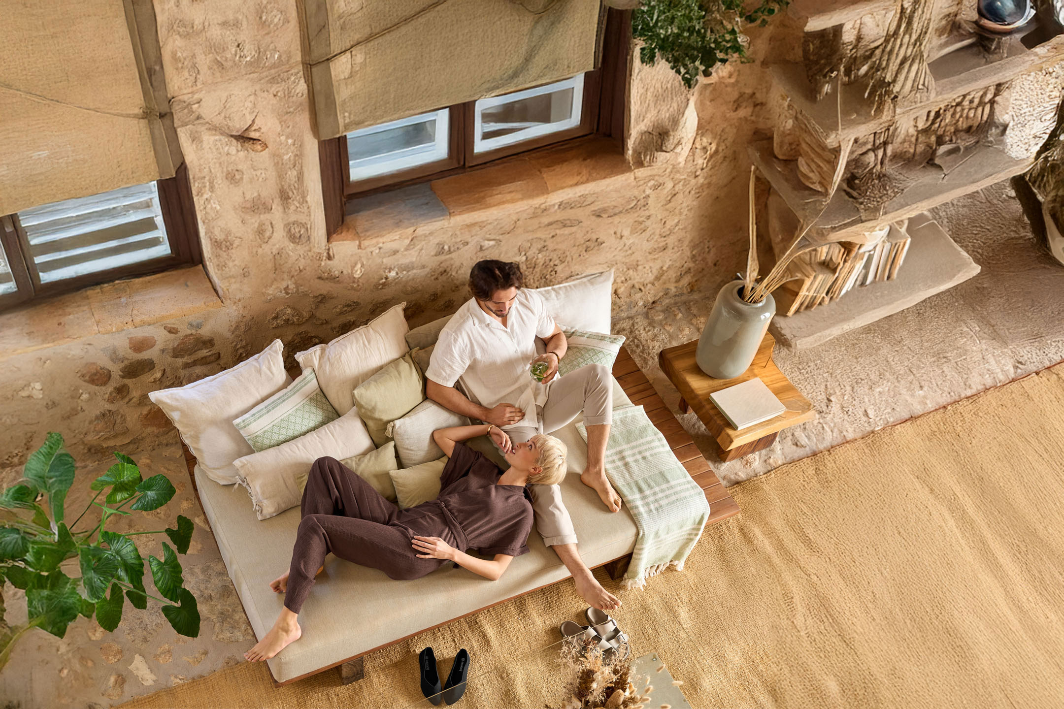 Couple relaxing on sofa, clothing and home accessories shown.