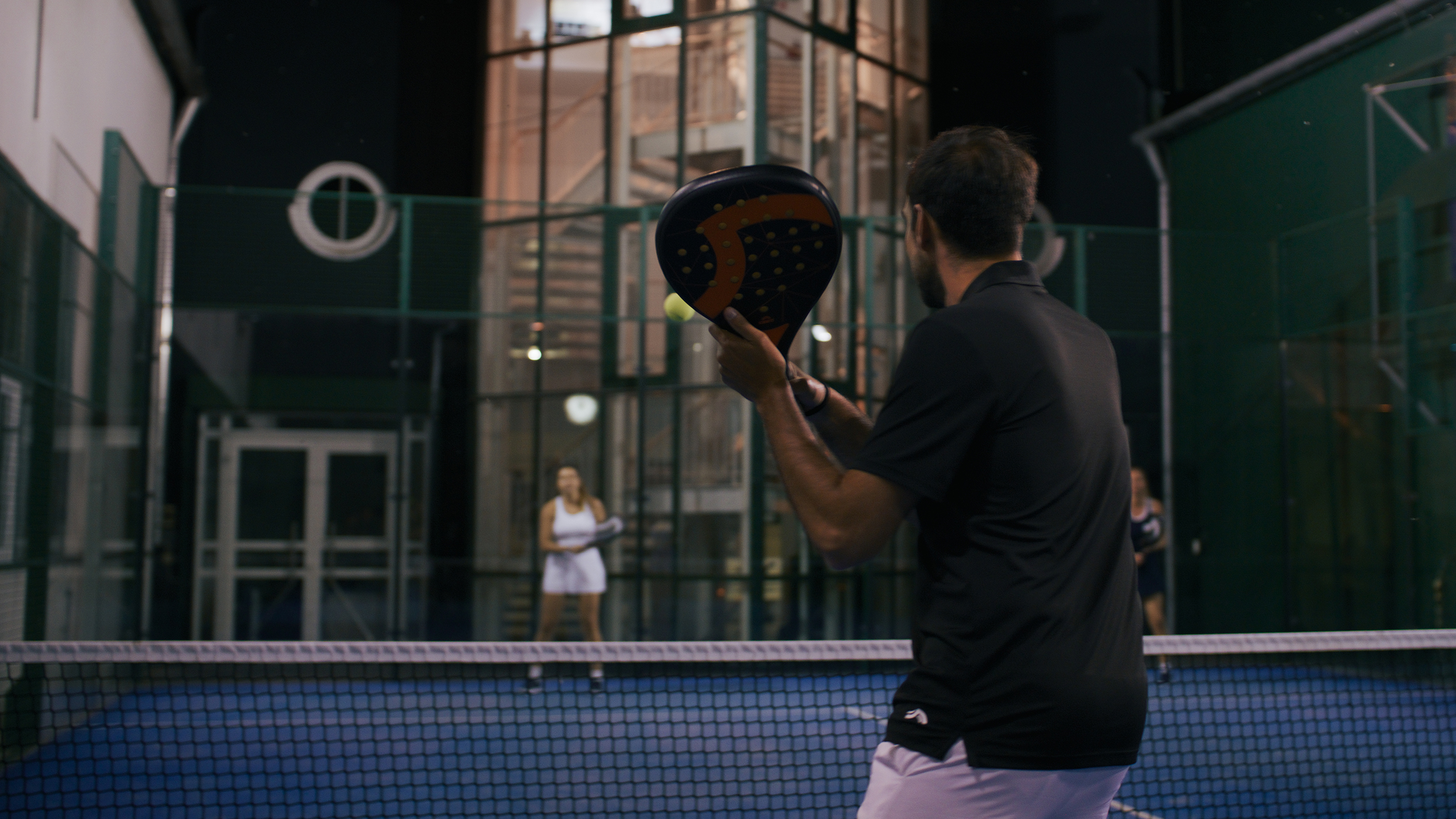 Paddle tennis: player with racket, night game.